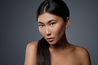 Gri arka planda genç ve güzel Asyalı kadın modelinin portresi