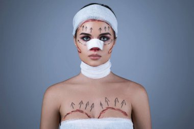 Plastik cerrahi kurbanlarının kavramsal görüntüsü. Yara ve bandajla sarılmış bir kadın başka bir ameliyat için hazırlanıyor..
