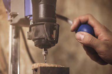 Marangoz atölyesindeki matkap üzerinde çalışıyor.