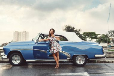 Genç, güzel ve mutlu bir kadın üstü açık bir araba kullanıyor.