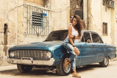 Kadın Havana sokaklarında eski arabanın yanında poz veriyor.
