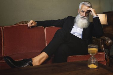 Şık ve yakışıklı sakallı kıdemli adam kum saatine bakıyor.