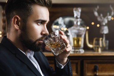 Bir bardak viskiyle yakışıklı sakallı adamın portresi.