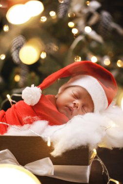 Noel Baba şapkası takan şirin bebek Noel Baba hediye kutusunda uyuyor. Mutlu Noeller ve mutlu yıllar..