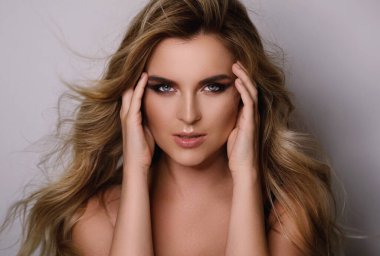 Güzel kıvırcık saçlı ve profesyonel makyajlı muhteşem bir kadının portresi.