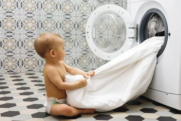 可爱的男婴在浴室的洗衣机旁边 — 图库照片