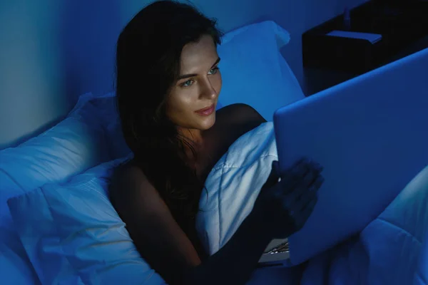 若く美しい女性は夜にラップトップコンピュータを使用しています — ストック写真