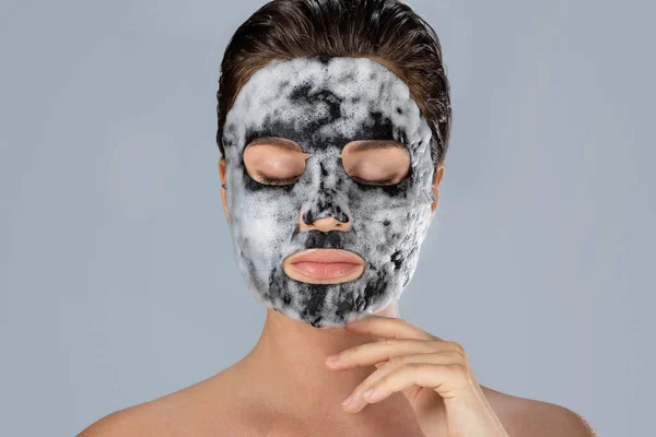 Ung Kvinna Med Bubbla Sheet Mask Ansiktet Grå Bakgrund — Stockfoto