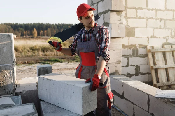 Professional bricklayer is sawing autoclaved concrete blocks