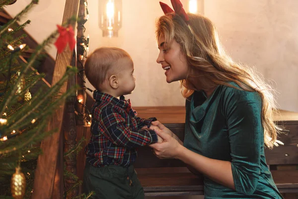 若い幸せな母親と彼女のかわいい息子はクリスマスや新年を祝っています — ストック写真