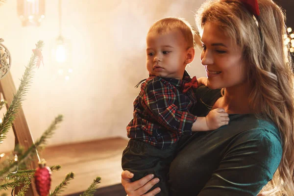 若い幸せな母親と彼女のかわいい息子はクリスマスや新年を祝っています — ストック写真