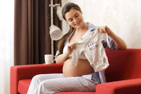 Mladá Těhotná Žena Dívá Bodysuit Pro Její Budoucí Dítě — Stock fotografie