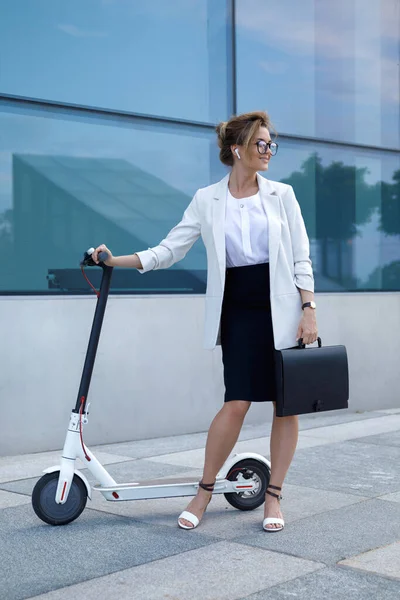 若くて美しい実業家が街の電動スクーターに乗る — ストック写真
