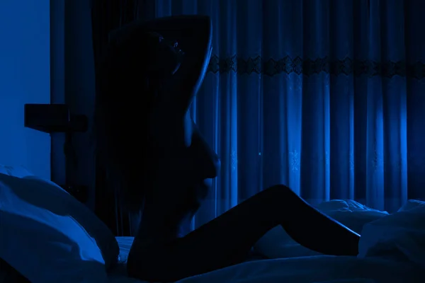 Işığında Yatağın Üzerinde Oturan Çıplak Kadın Silueti — Stok fotoğraf