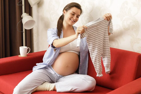 Mladá Těhotná Žena Dívá Bodysuit Pro Její Budoucí Dítě — Stock fotografie