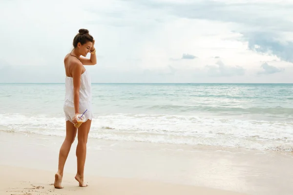 身穿白色连衣裙的漂亮女人在海滩上散步 喝了一杯冰咖啡 — 图库照片