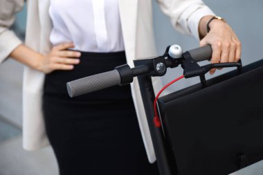 Kadın ellerinin yakın çekimi ve elektrikli scooter direksiyonu.