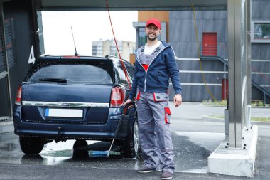 Profesyonel oto yıkama işçisi müşterinin arabasını yıkıyor.