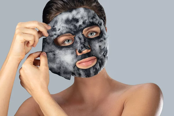 Ung Kvinna Med Bubbla Sheet Mask Ansiktet Grå Bakgrund — Stockfoto