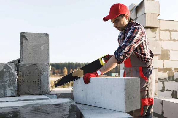 Professional bricklayer is sawing autoclaved concrete blocks