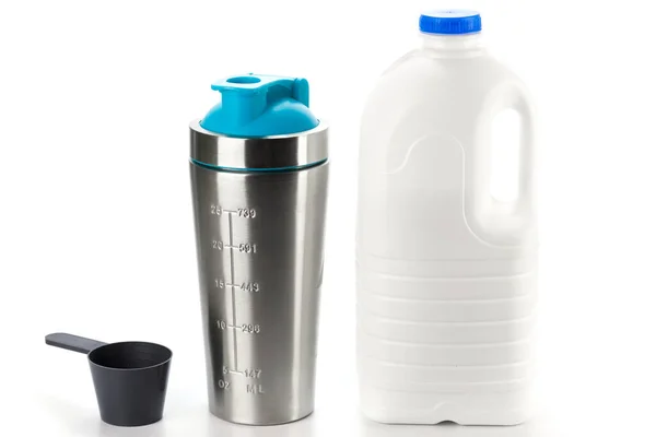 Metal protein shaker and big bottle of milk on white background