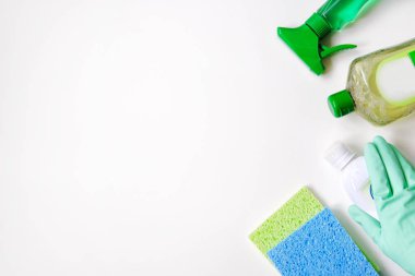 Temizlik aksesuarları. Beyaz arka planda düz yeşil ve beyaz temizlik malzemeleri var. Plastik şişelerdeki Deterjanlar. Üst Manzara. Kapat..