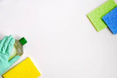 Temizlik aksesuarları. Beyaz arka planda yeşil ve beyaz temizlik malzemelerinin üst görüntüsü. Plastik şişelerdeki Deterjanlar. Kapat..