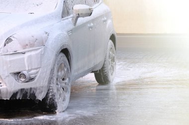 Araba yıkamada köpüklü sabun, oto yıkama istasyonunda beyaz araba. Su ve beyaz sabun akıyor..