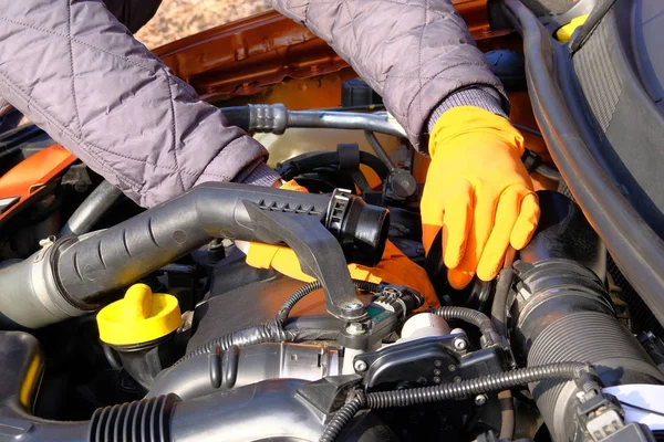 Automobile maintenance concept. Hands of driver in orange rubber