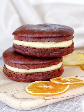 Dessert - Chocolate Cheesecake Sandwich with milk orange filling. Decoration with fruit. Vertical view.