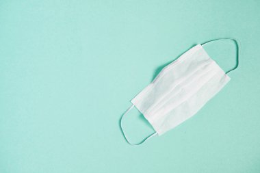 Sağlık ve cerrahi konsept. Mavi arka planda beyaz tıbbi maske. Kirliliğe karşı yüz maskesi koruması, virüs, grip ve koronavirüs, üst görünüm.