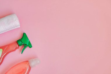 Sprey şişedeki temizlikçi. Pembe arka planda hijyenik ürün ve kumaşın üst görüntüsü. - Yakın çekim. Boşluğu kopyala.