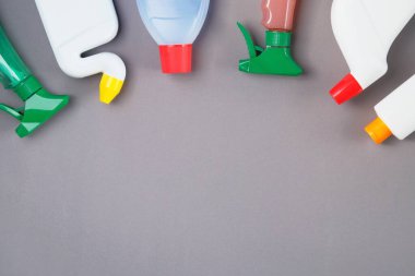 Gri arka planda temizlik ve çamaşır ürünleri yatıyordu. Plastik şişelerde ve spreylerde deterjan. Hizmet kavramı. Üst Manzara. Boşluğu kopyala.