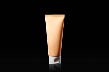 Siyah arka planda turuncu krema şişesi, konsept güzellik