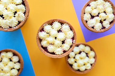 Reçelli ve kremalı sepetler. Pastalı yakın çekim, turuncu ve mavi arka planda düz uzanma, doyurucu bir kahvaltı.