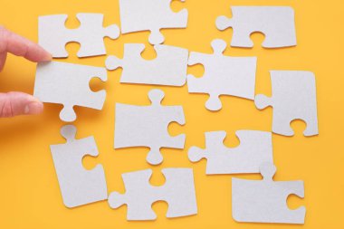 El, parlak sarı arka planda bir yapboz parçası tutuyor. iş sorunu çözme kavramı