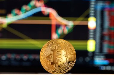 Şifreleme para birimlerinin büyüme ve düşüşünün grafiğinin önündeki masada bitcoin var. sanal para kavramı