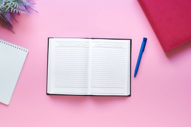 Minimalist masaüstü - günlük, kalem, notlar için not defteri, pembe arka planda düz uzanmış. ev çalışma alanı kavramı