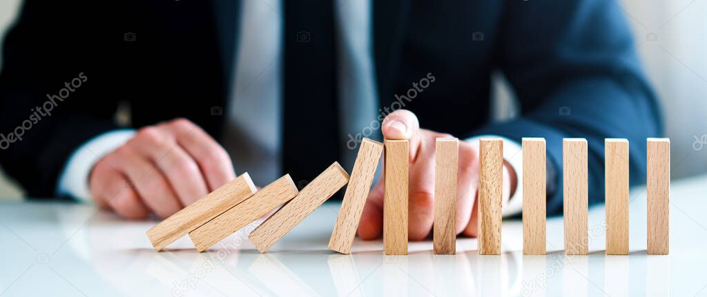 businessman stops falling wooden blocks. business solutions concept
