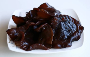 Beyaz zemin üzerinde siyah jöle veya Auricularia politricha (jamur kuping hitam). 