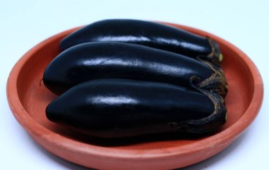 Beyaz arka planda kırmızı biberler çömlek tabağında.