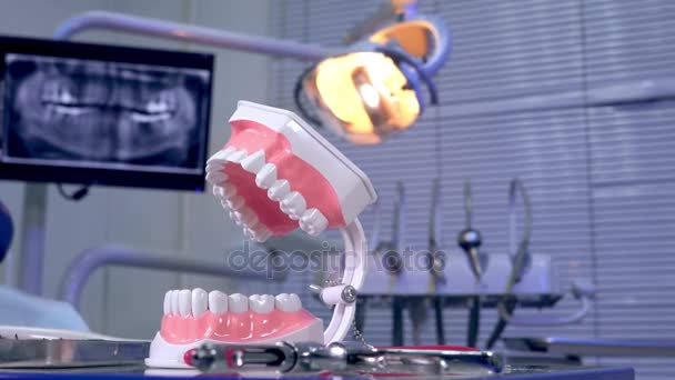 Tooth model instruments on the dentist table and panoramic x-ray image in the background — Stock Video