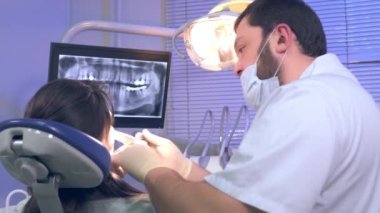 Diş hekimi diş Bayan hasta klinikte tedavi öncesi inceliyor