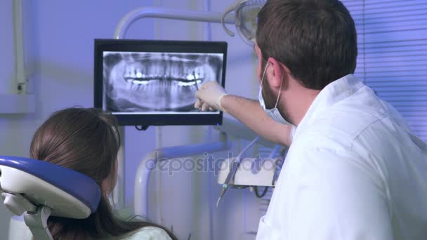 Odontólogo muestra una mujer paciente imagen de rayos X de dientes durante el tratamiento en la clínica dental — Vídeo de stock