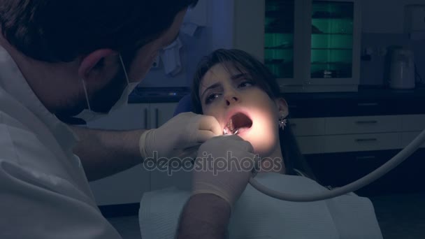 Dentista durante il trattamento esamina denti ragazza paziente clinica privata . — Video Stock
