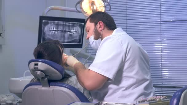 Стоматолог на работе с пациентом в офисе частной клиники — стоковое видео