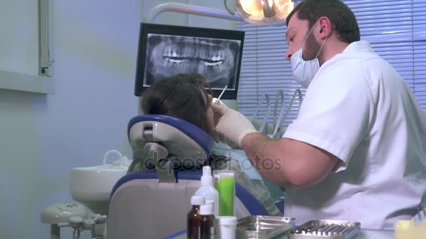 Dentist at work shows a patient x-ray images of teeth — Stock Video