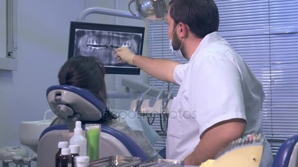 Dentista mostra um paciente radiografia de dentes e continua a trabalhar — Vídeo de Stock