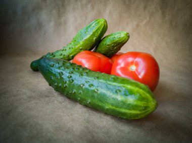 Koyu arkaplanda taze domates ve salatalık. Kırmızı domatesler ve yeşil salatalıklar yaklaşın.