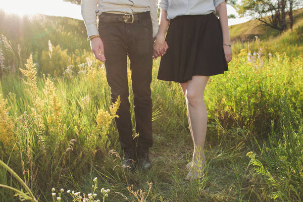 Young couple holding hands. Girl and guy in nature. Love